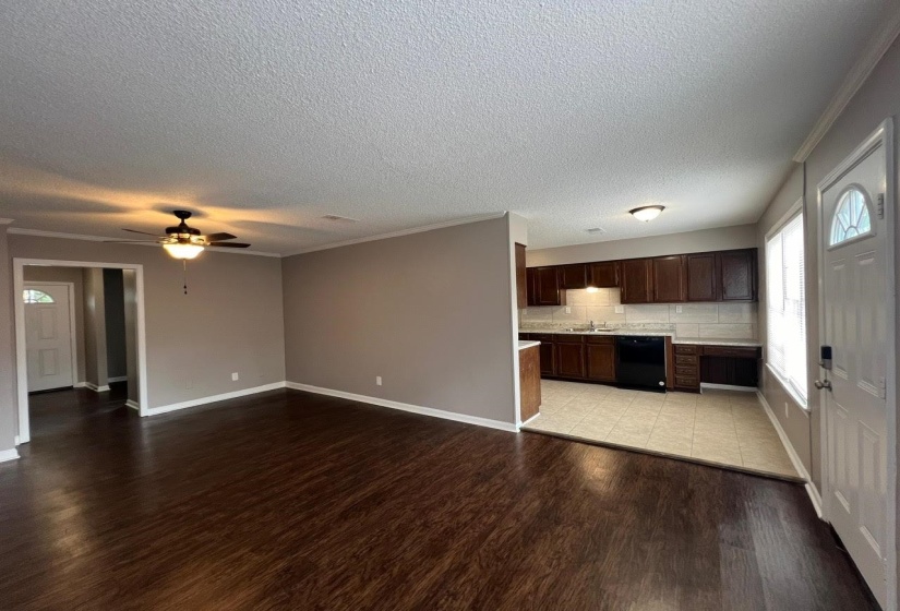 Unfurnished living room featuring sink, light wood-type flooring, a textured ceiling, ceiling fan, and ornamental molding