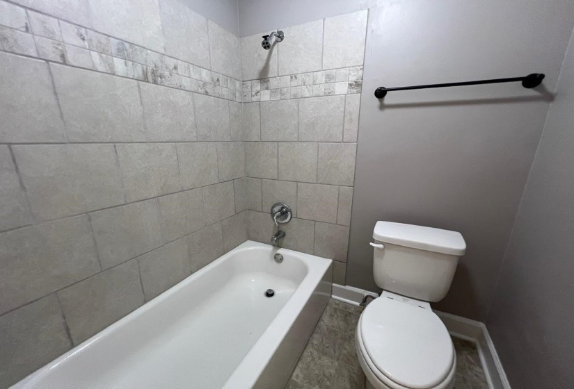 Bathroom with toilet, tile patterned floors, and tiled shower / bath combo