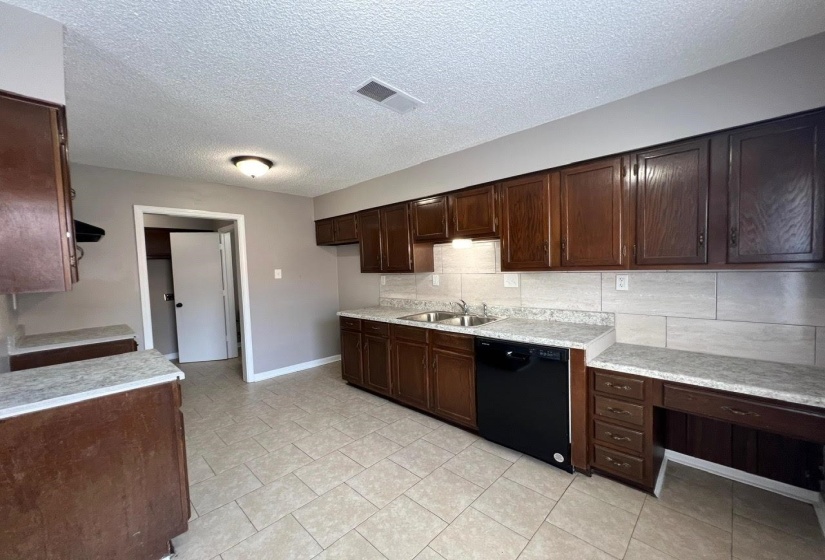 Kitchen featuring light tile patterned flooring, dishwasher, decorative backsplash, dark brown cabinetry, and sink