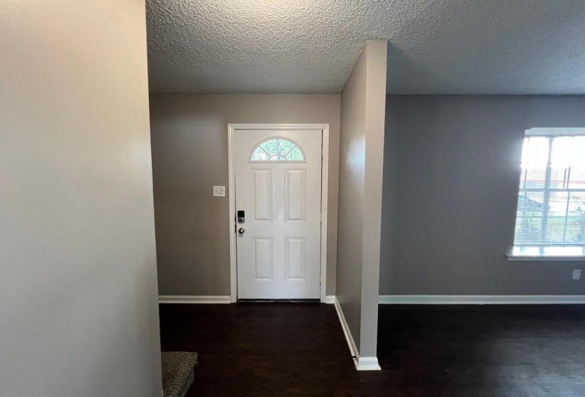 Entryway with a textured ceiling and dark hardwood / wood-style floors