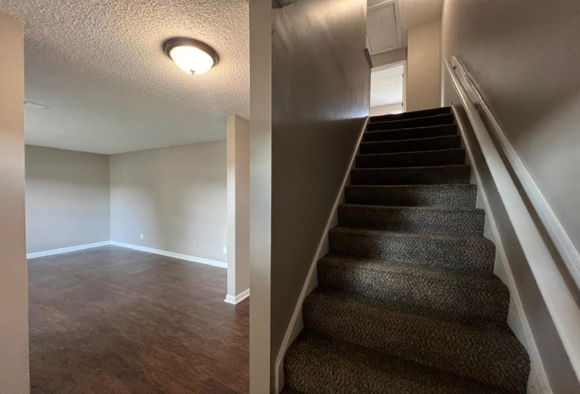 Stairway featuring a textured ceiling and hardwood / wood-style floors