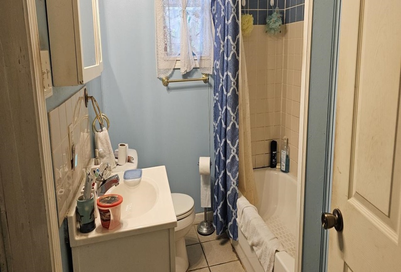 Full bathroom with vanity, toilet, shower / tub combo with curtain, and tile patterned floors