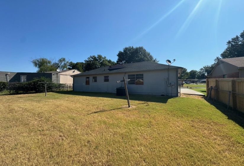 Rear view of property with central air condition unit and a lawn