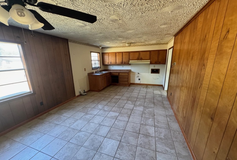Kitchen featuring ceiling fan, wood walls, and light tile patterned floors