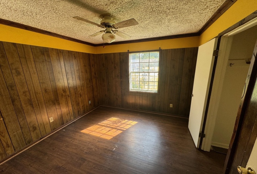 Spare room featuring ceiling fan, crown molding, dark wood-type flooring, and a textured ceiling