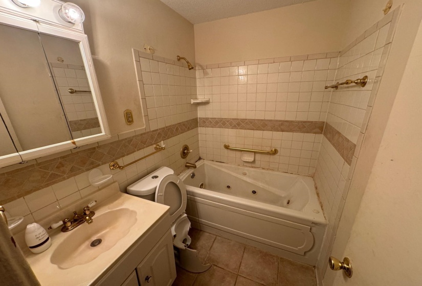 Full bathroom with decorative backsplash, toilet, vanity, tile patterned floors, and tiled shower / bath combo
