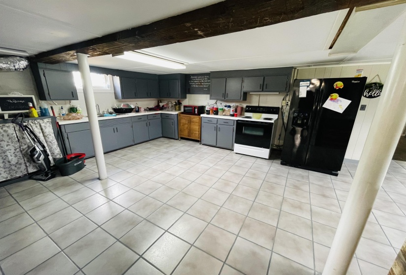 Kitchen with gray cabinets, light tile patterned flooring, sink, and black appliances