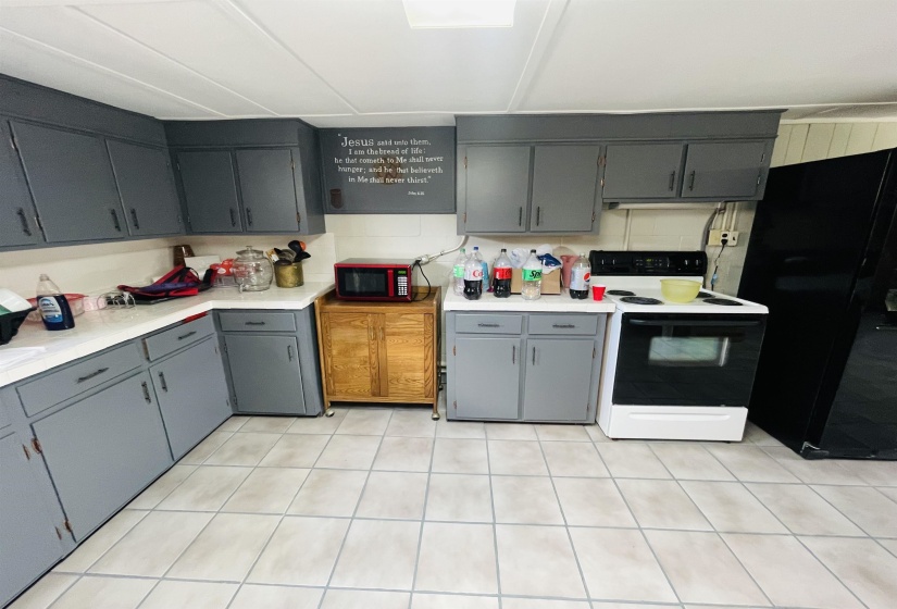 Kitchen featuring black fridge, white electric range, backsplash, and gray cabinetry