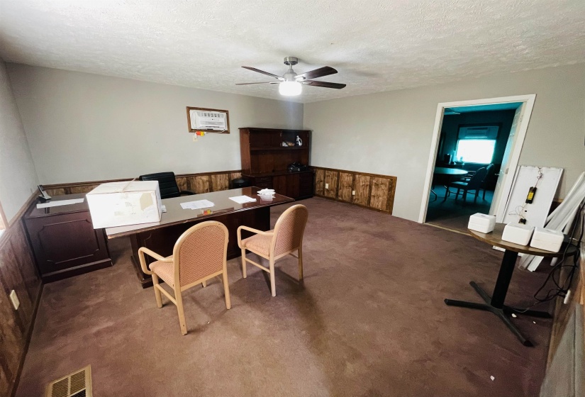 Carpeted home office with ceiling fan and a textured ceiling