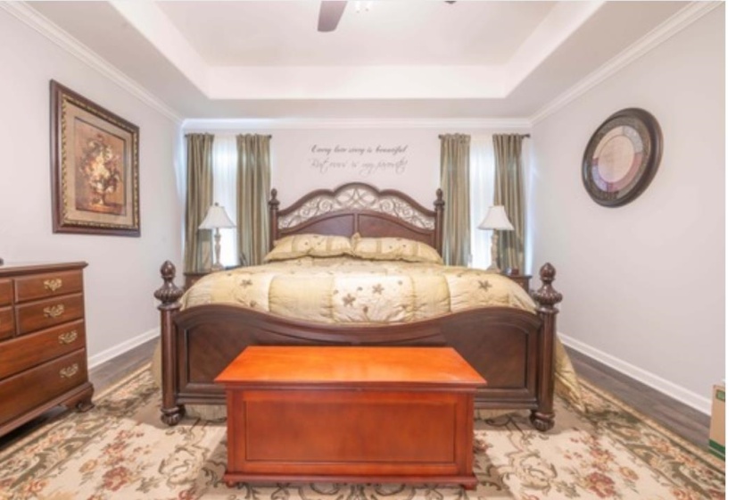 Bedroom with ornamental molding, light wood-type flooring, a tray ceiling, and ceiling fan