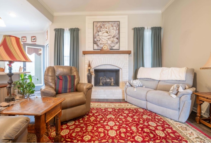 Living room with a brick fireplace, crown molding, and a healthy amount of sunlight