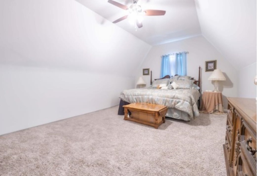Bedroom featuring vaulted ceiling, light carpet, and ceiling fan