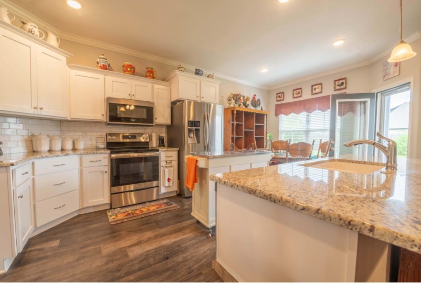 Kitchen featuring hanging light fixtures, white cabinetry, sink, and stainless steel appliances