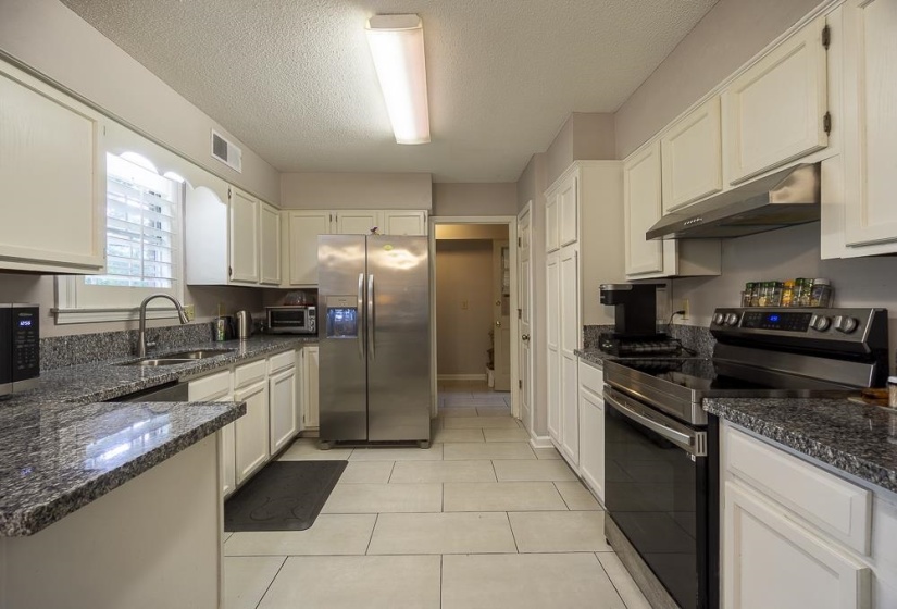 Kitchen, white cabinetry, stainless steel appliances, and granite countertops