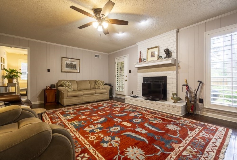 Fireplace has a raised hearth and is flanked by windows.