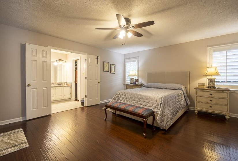 Primary Bedroom with multiple windows, dark hardwood floors, and ceiling fan