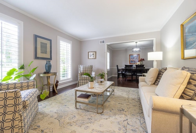 Living room with ornamental molding, a notable chandelier, and hardwood / wood-style flooring