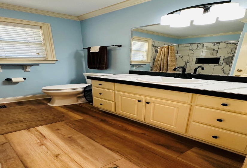 Bathroom featuring a shower stall, wood finished floors, toilet, and crown molding