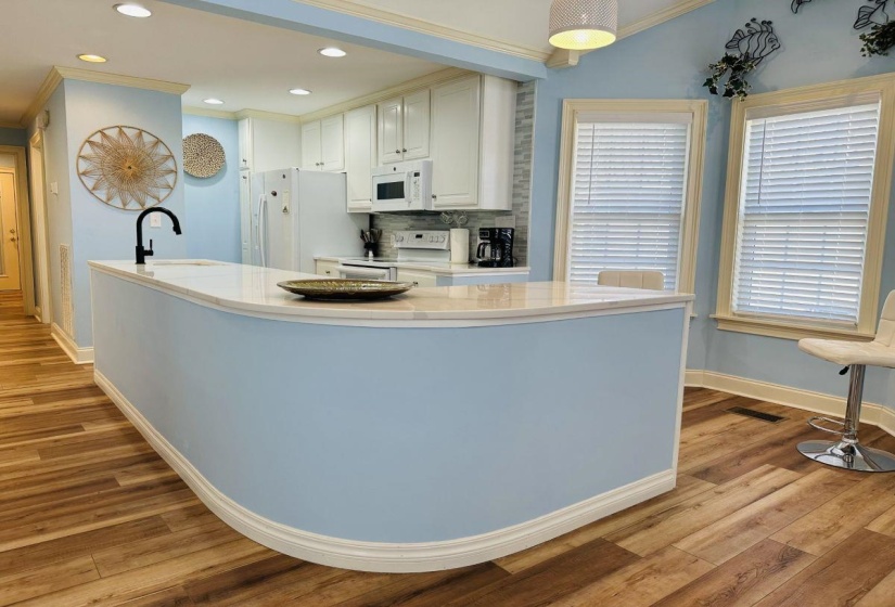 Kitchen with white appliances, wood finished floors, a sink, baseboards, and light countertops