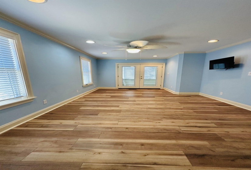 Spare room featuring french doors, crown molding, baseboards, and wood finished floors