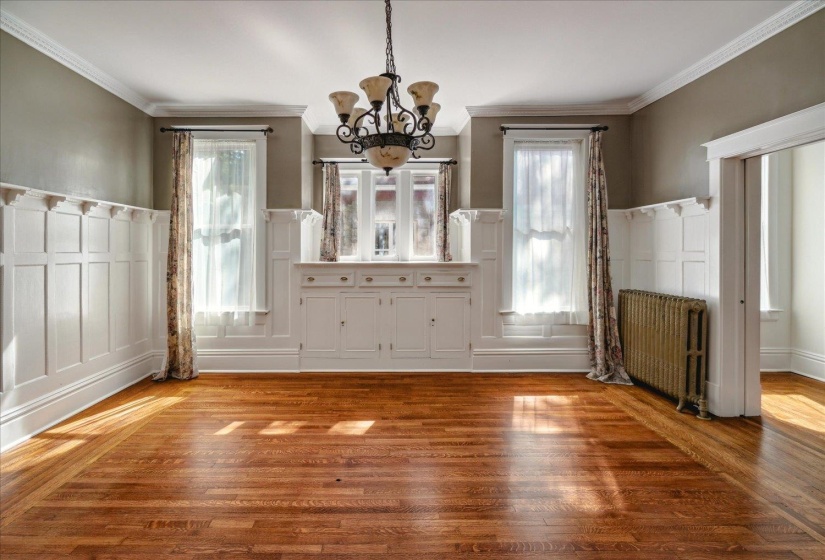Unfurnished dining area with ornamental molding, radiator heating unit, a healthy amount of sunlight, and hardwood / wood-style floors