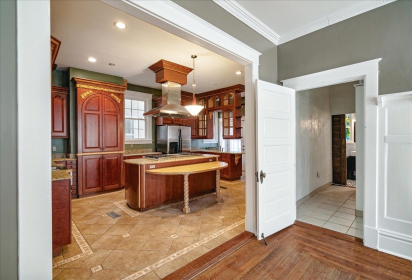 Kitchen featuring island exhaust hood, stainless steel fridge, crown molding, a center island, and pendant lighting