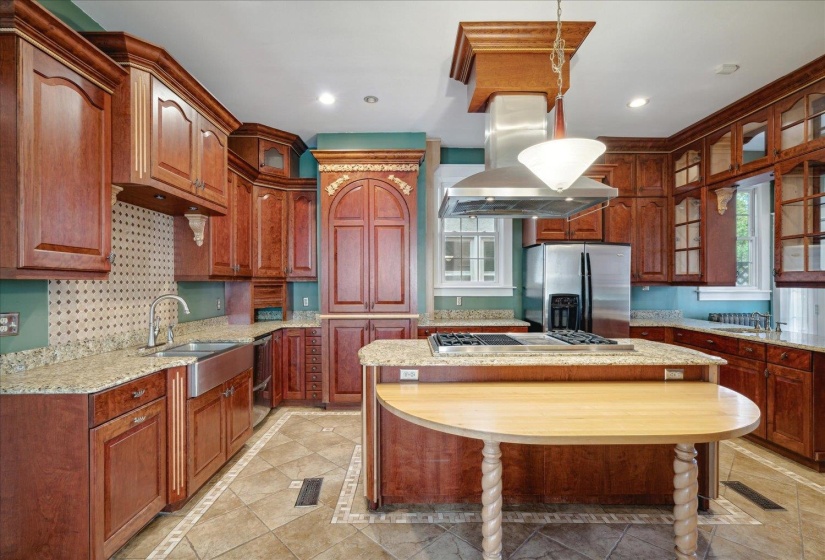 Kitchen featuring hanging light fixtures, a kitchen island, island range hood, stainless steel appliances, and sink