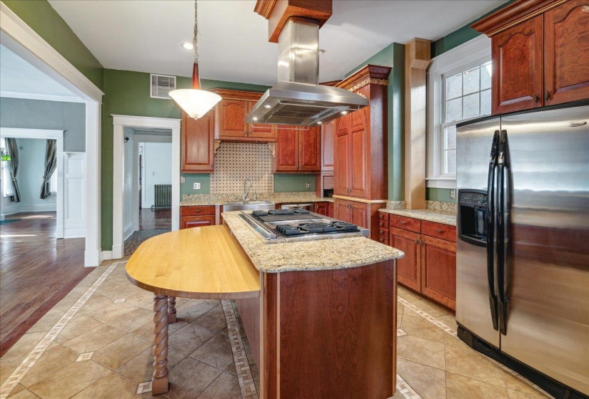Kitchen with tasteful backsplash, hanging light fixtures, appliances with stainless steel finishes, island range hood, and light hardwood / wood-style floors