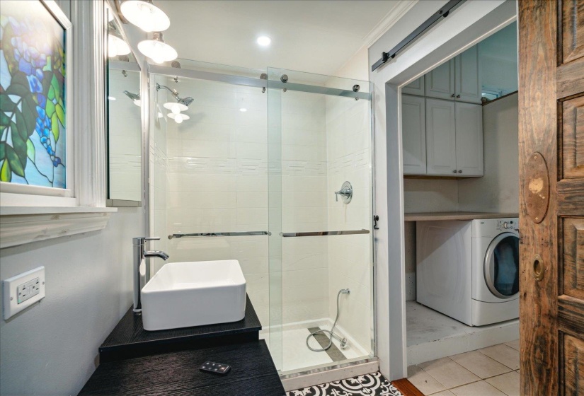 Bathroom featuring an enclosed shower, tile patterned floors, sink, and washer / clothes dryer