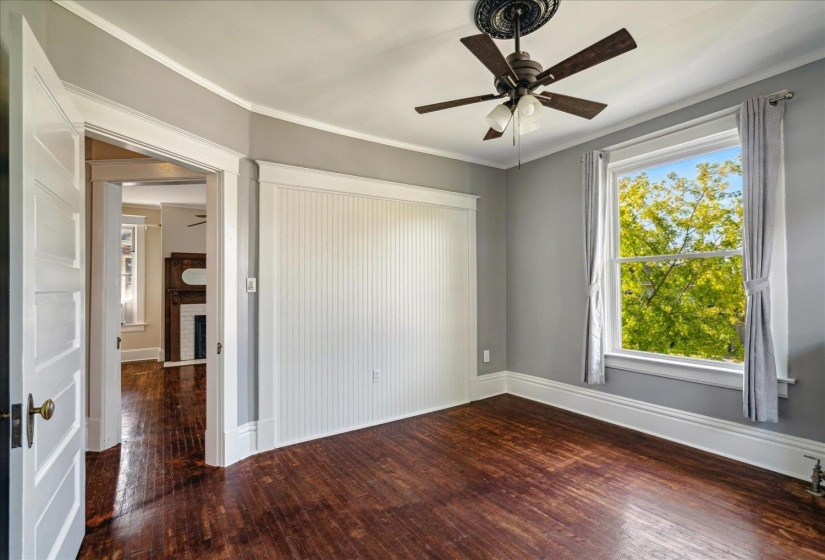 Unfurnished room with a brick fireplace, ornamental molding, ceiling fan, and dark hardwood / wood-style flooring