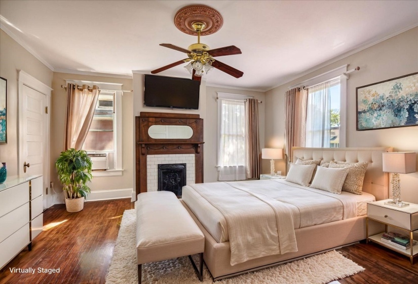 Bedroom with cooling unit, dark wood finished floors, crown molding, a fireplace, and ceiling fan