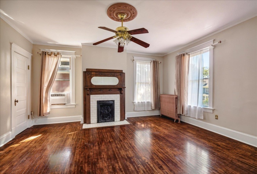 Unfurnished living room with radiator, cooling unit, dark hardwood / wood-style flooring, and a brick fireplace