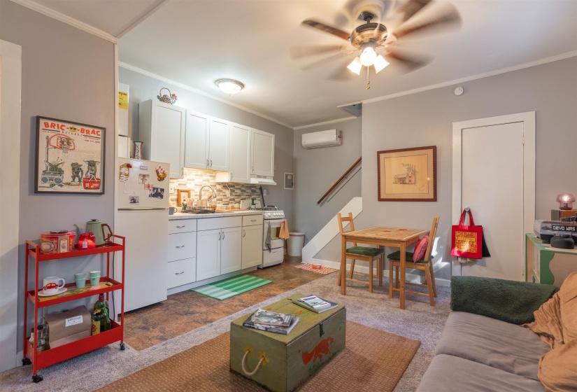 Living room with an AC wall unit, sink, ornamental molding, and carpet flooring