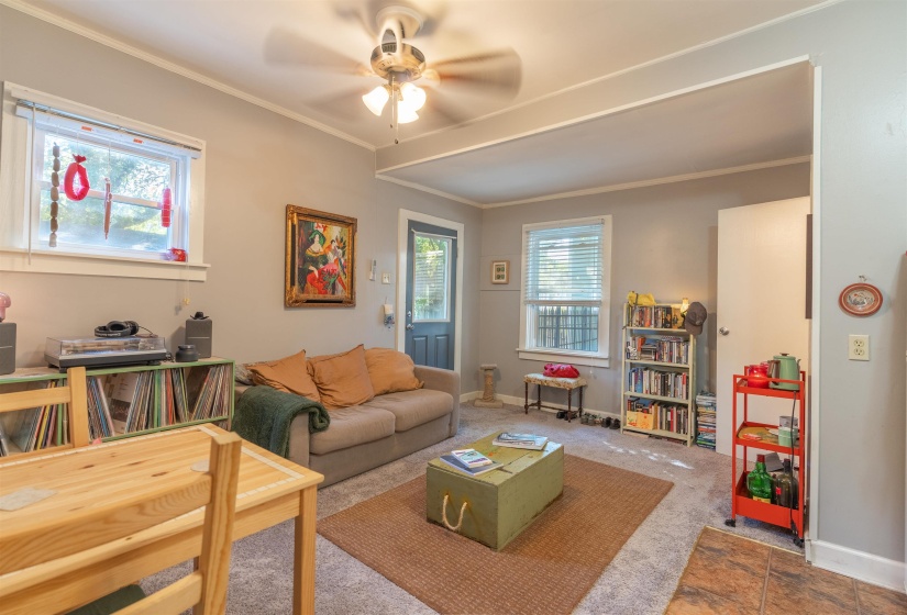 Carpeted living room with ceiling fan, ornamental molding, and a wealth of natural light