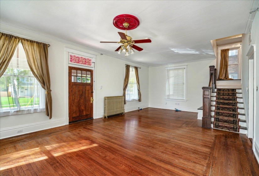 Unfurnished living room featuring hardwood / wood-style floors, ceiling fan, radiator heating unit, and plenty of natural light