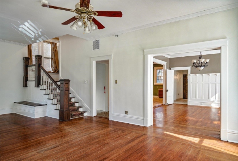 Unfurnished living room with ornamental molding, hardwood / wood-style floors, and ceiling fan with notable chandelier