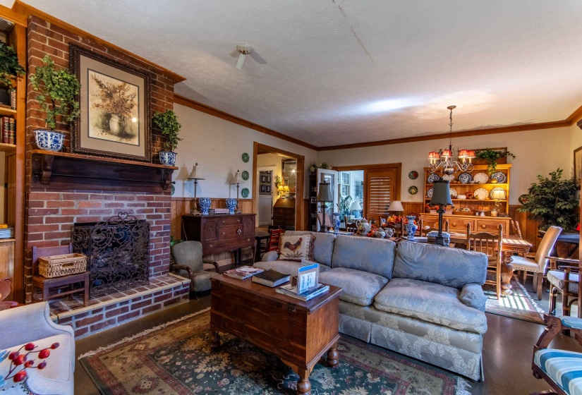Living room with ornamental molding, a chandelier, a textured ceiling, and a fireplace