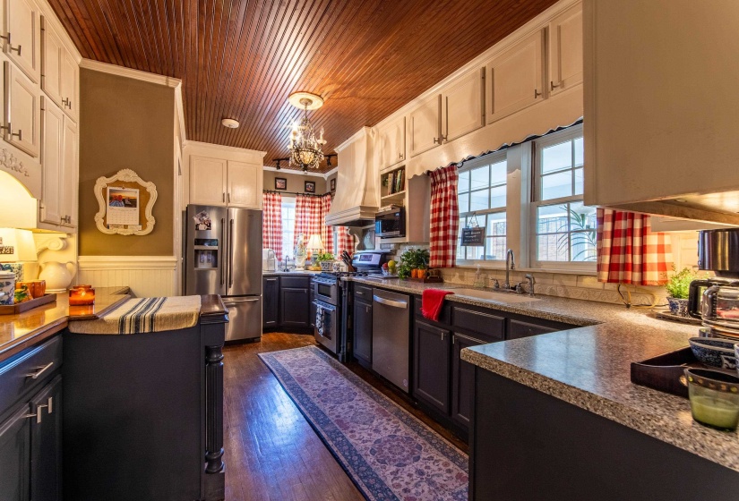 Kitchen with wood ceiling, sink, white cabinets, stainless steel appliances, and dark hardwood / wood-style flooring