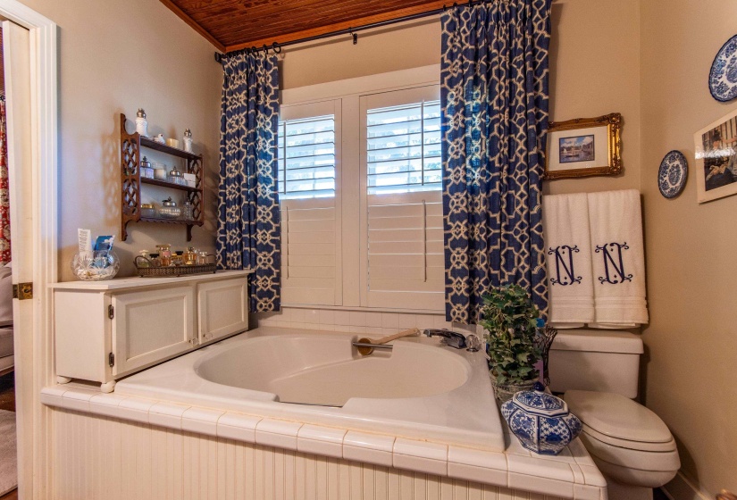 Bathroom with toilet, wooden ceiling, and a bathing tub