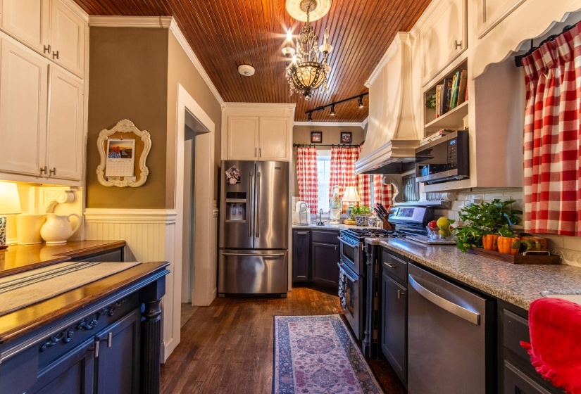 Kitchen featuring white cabinets, appliances with stainless steel finishes, ornamental molding, and wooden ceiling