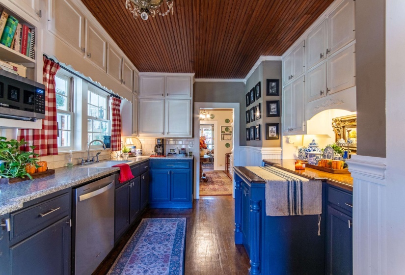 Kitchen with white cabinetry, dark wood-type flooring, blue cabinetry, stainless steel appliances, and crown molding