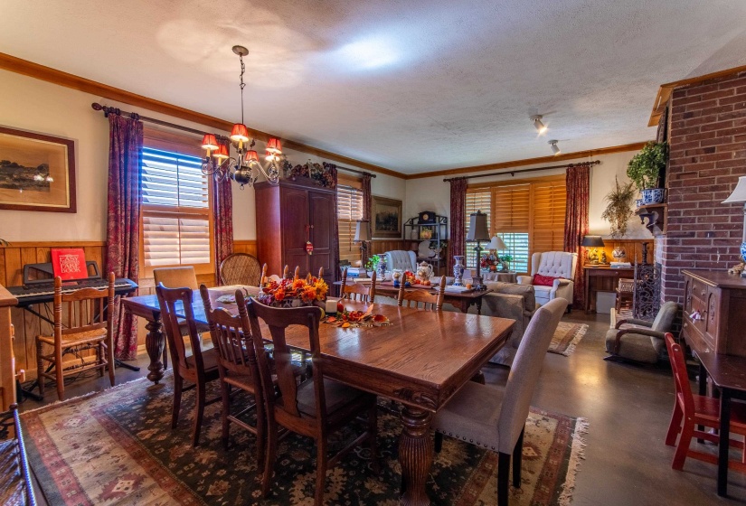 Dining area featuring a textured ceiling, crown molding, wood walls, and an inviting chandelier