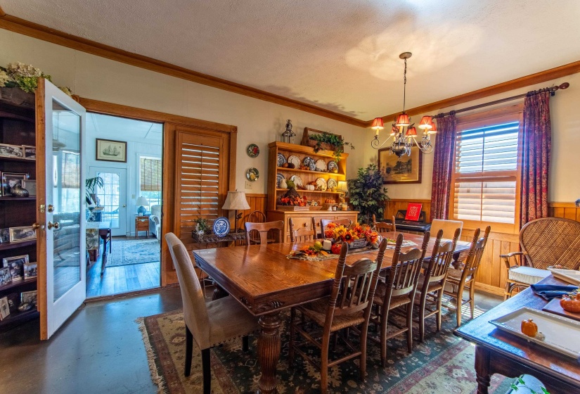 Dining room featuring a textured ceiling, wood walls, ornamental molding, and an inviting chandelier