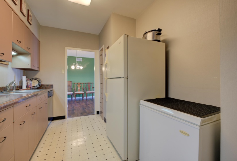 Kitchen with an inviting chandelier, sink, pendant lighting, and white refrigerator