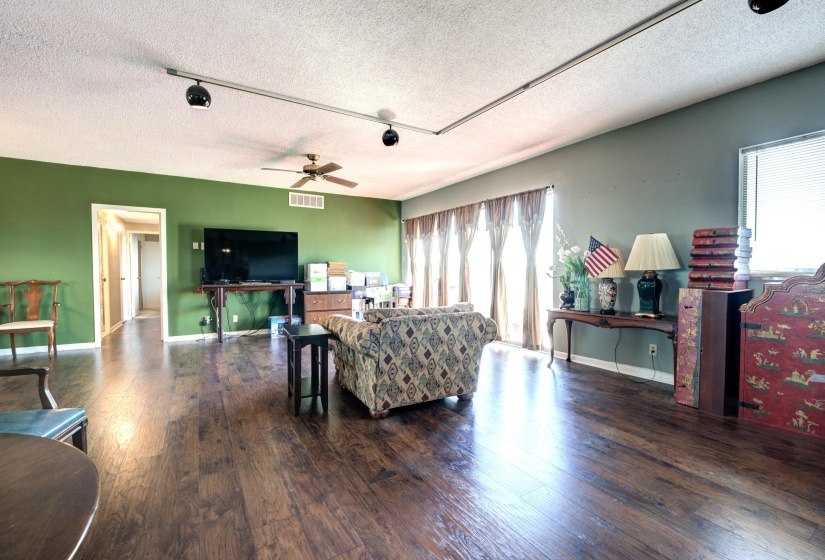 Living room with a textured ceiling, dark hardwood / wood-style floors, ceiling fan, and track lighting