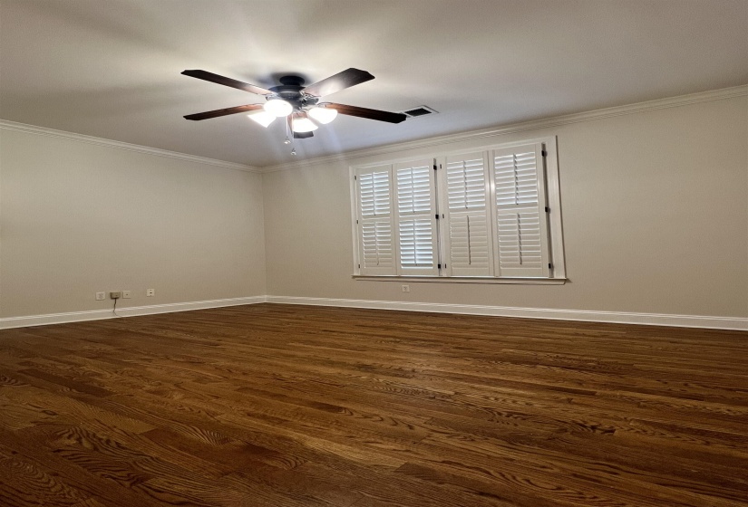 Empty room with crown molding, ceiling fan, and dark wood-type flooring