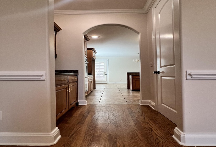 Corridor featuring an inviting chandelier, dark wood-type flooring, and ornamental molding