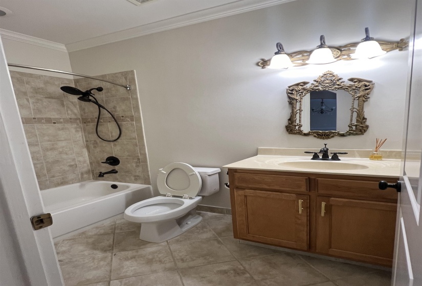 Full bathroom featuring ornamental molding, vanity, tiled shower / bath combo, tile patterned flooring, and toilet
