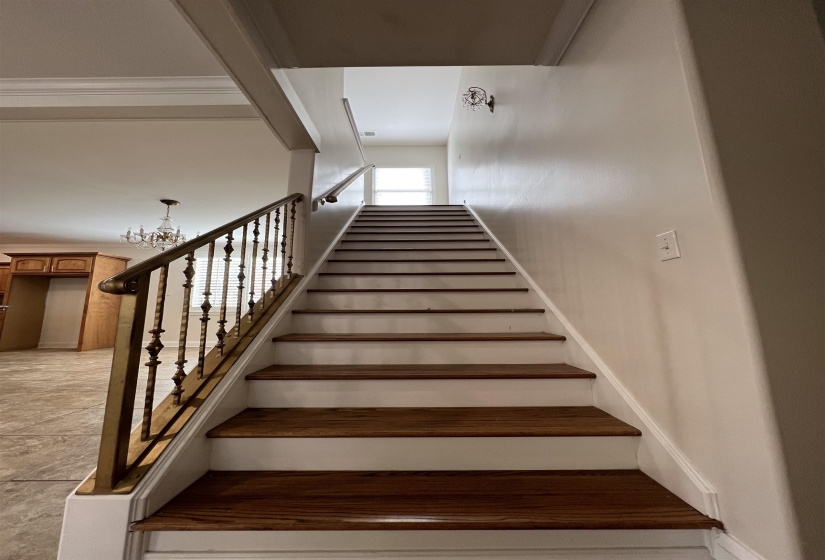 Staircase with an inviting chandelier and ornamental molding