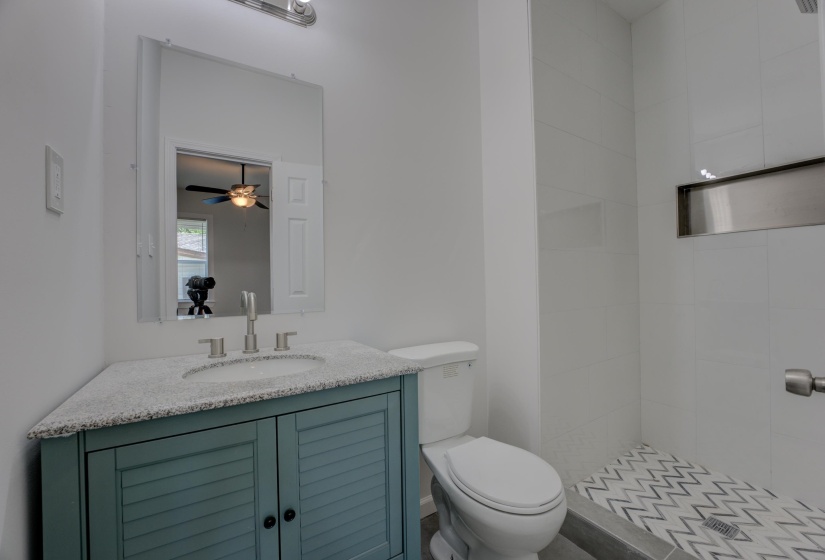 Bathroom featuring toilet, a tile shower, vanity, and ceiling fan